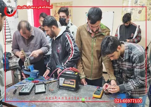 هنر جو های دوره اموزش برق خودرو در کنار استاد دوره در حال اموزش تست قطعات استارت با دستگاه مولتی متر در گارگاه اموزشگاه برق خودرو