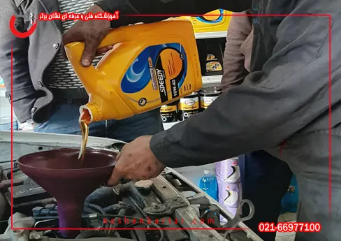 هنرجوی دوره تعویض روغنی در حال ریختن روغن در موتور خودرو میباشد در کارگاه اموزشگاه تعویض روغنی نشان برتر اموزشگاه سرویس و نگهداری نشان برتر
