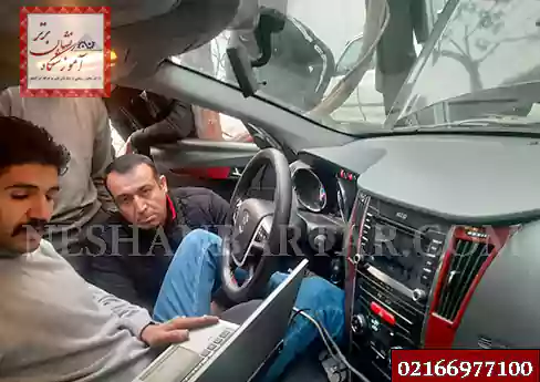 فردی در حال کار با دستگاه دیاگ و لپ تاپ در ماشین برای آموزش برق خودرو باطریسازی