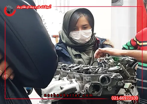 دختر جوانی با ماسک در حال دیدن آموزش در دوره مکانیکی خودرو