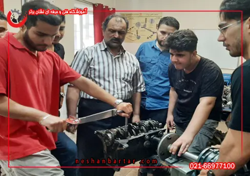 هنرجویی با لباس قرمز در دوره آموزش مکانیک خودرو در حال باز کردن موتور خودرو